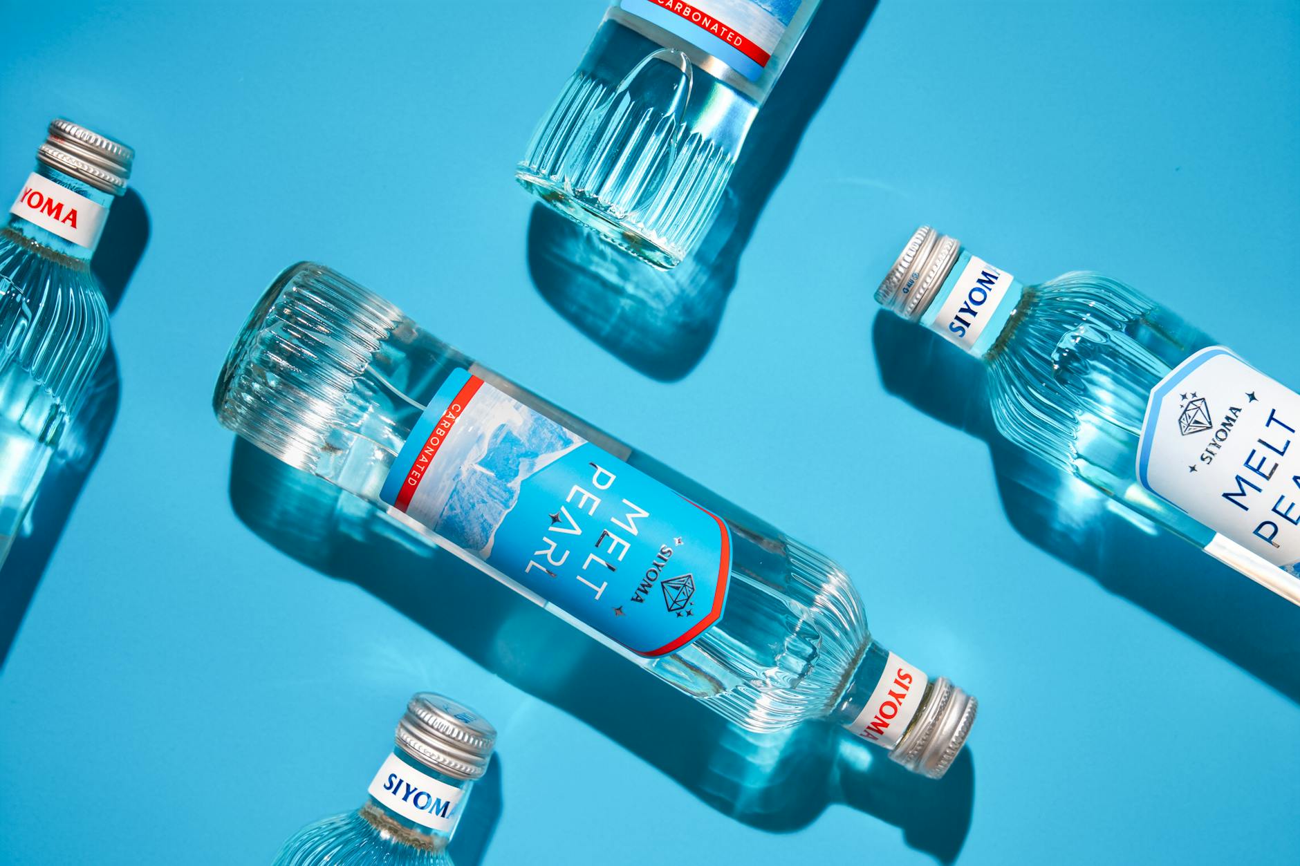 Sparkling water bottles laid on a vibrant blue surface showcasing freshness and clarity.