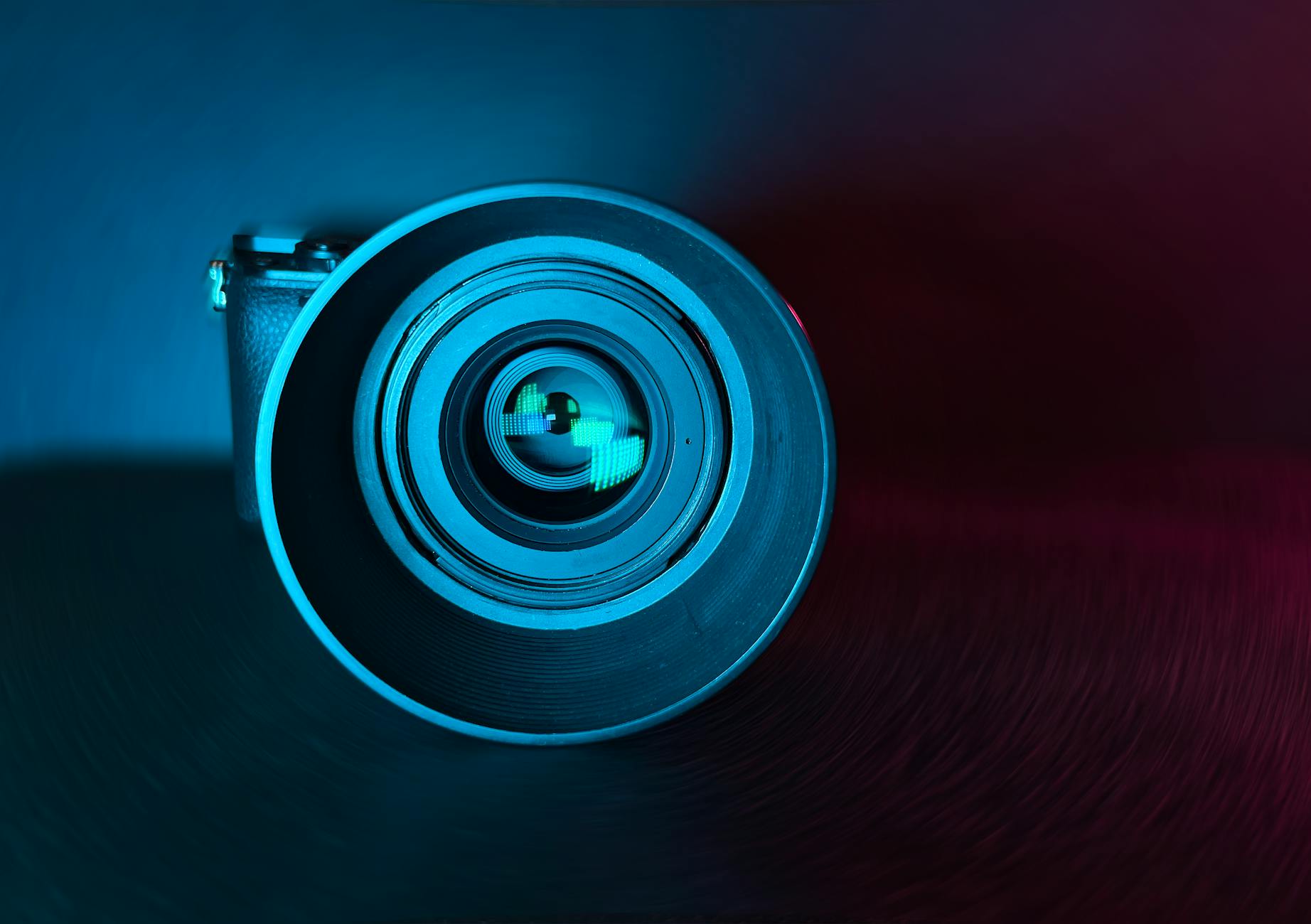 A striking artistic photo of a camera lens bathed in blue and red light.