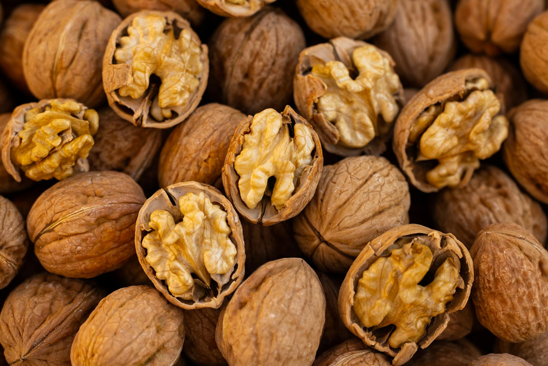 Detailed close-up of walnuts with shells and halves, showing texture and pattern.