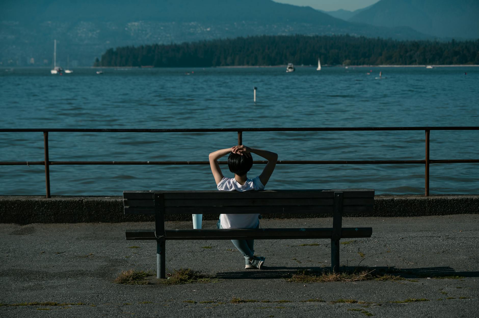 Woman sitting on a bench by the Vancouver coast enjoying the serene ocean view.